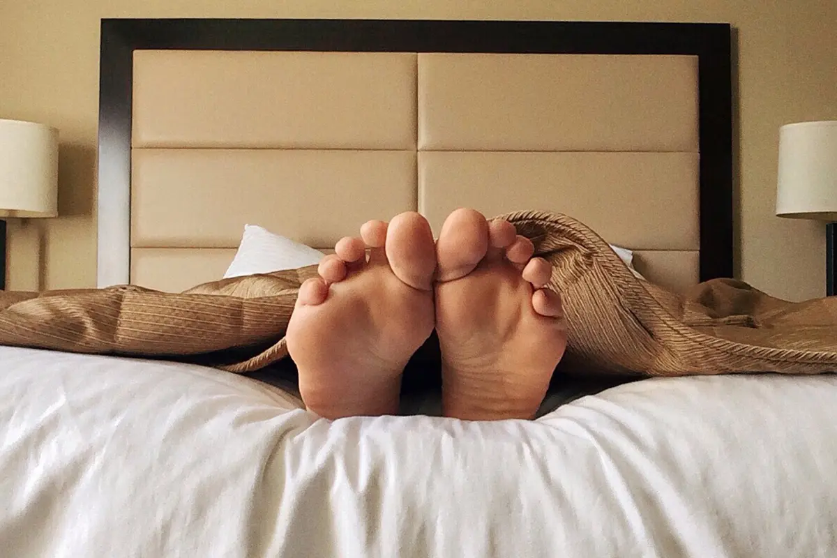 Person Lying a Bed with their Feet Sticking Out
